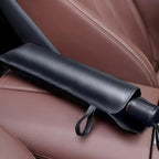 Black umbrella folded and placed inside a car seat