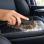 Horsehair detailing brush cleaning a black leather car seat